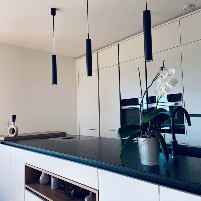 Moderne Küche mit eleganten Pendelleuchten und einer Orchidee auf der Arbeitsplatte.