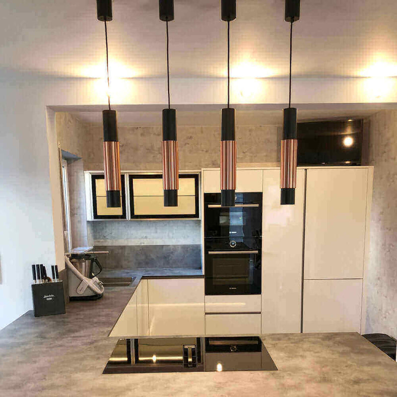 Moderne Küche mit eleganten Pendelleuchten, Hochglanz-Geräten und ansprechendem Design.