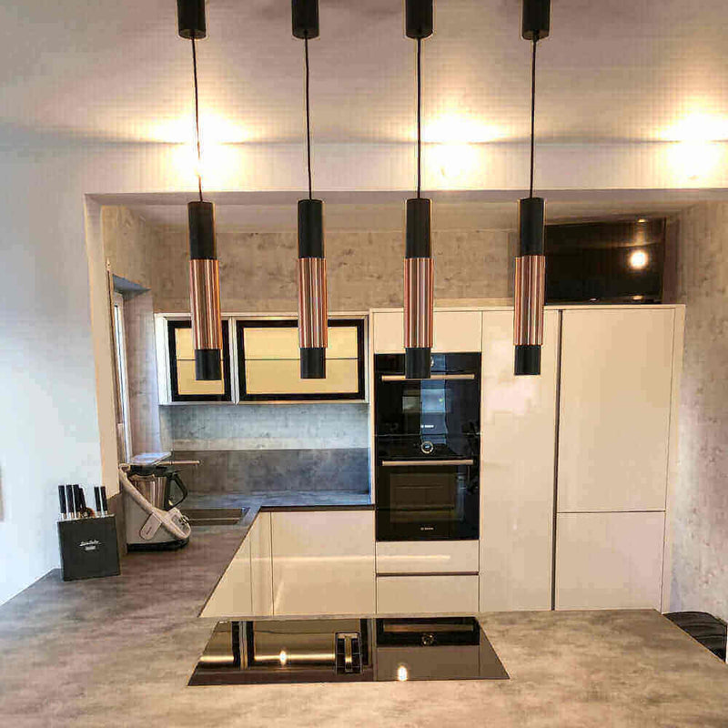Moderne Küche mit eleganten Pendelleuchten, Hochglanz-Geräten und ansprechendem Design.