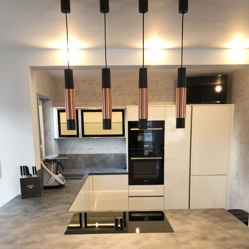 Moderne Küche mit eleganten Pendelleuchten, Hochglanz-Geräten und ansprechendem Design.