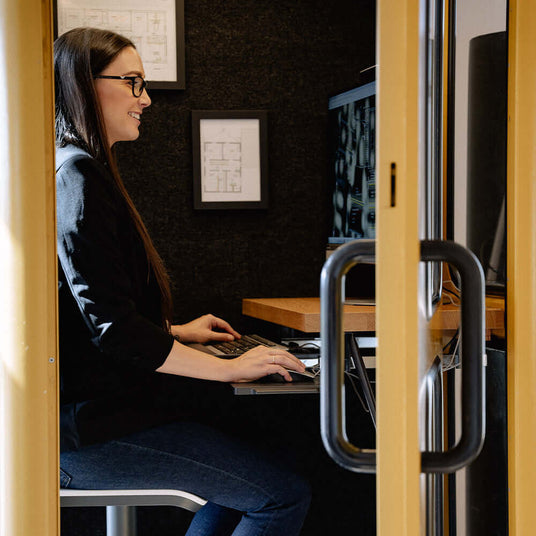 Frau im Büro, arbeitet am Computer in einem geschlossenen Raum mit kreativen Statistiken im Hintergrund.
