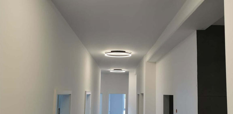 Heller Flur mit modernen Deckenleuchten und weißen Wänden, die eine ruhige Atmosphäre schaffen.