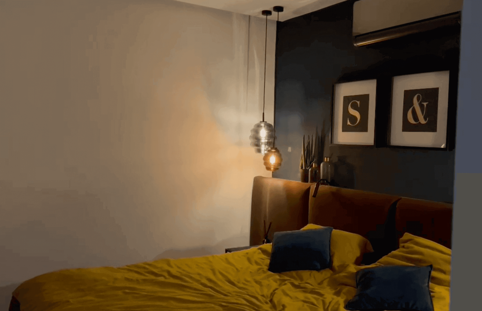 Moderne Schlafzimmergestaltung mit gelber Bettdecke und stilvollen Bildern an der Wand.