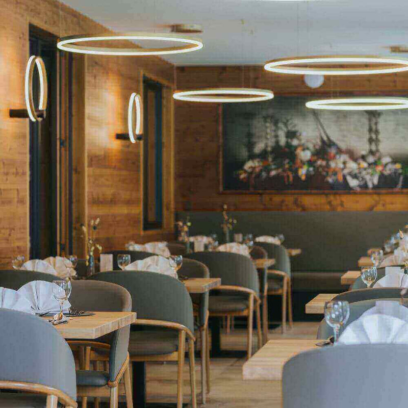 Modernes Restaurant mit eleganten runden Leuchten, stilvollen Tischen und gemütlichem Holzinterieur.