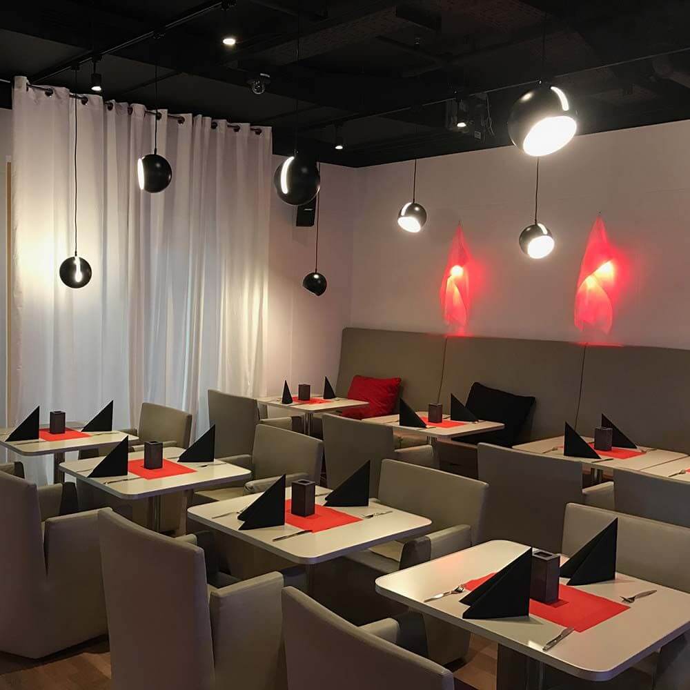 Elegantes Restaurant mit stilvoller Beleuchtung und gedeckten Tischen in modernen Farben.