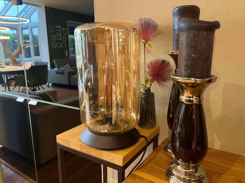 Moderne Glaslampe im eleganten Design neben Kerzenhaltern in stilvollem Wohnzimmer.