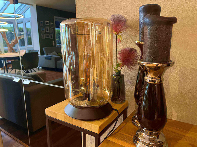 Moderne Glaslampe im eleganten Design neben Kerzenhaltern in stilvollem Wohnzimmer.