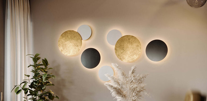 Moderne Wandgestaltung mit leuchtenden runden Wanddekoren in Gold, Schwarz und Weiß.