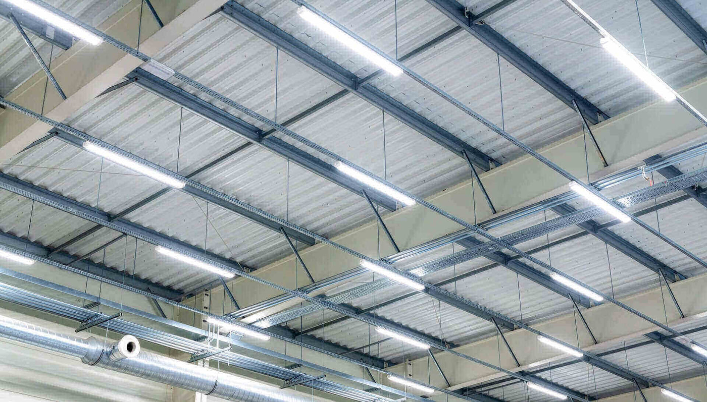 Industriehalle mit modernen LED-Deckenleuchten und Metallträgern, großer Raum für effiziente Belichtung.