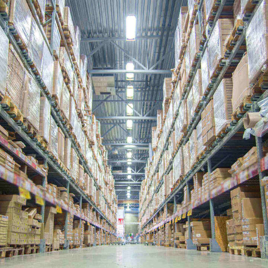 Großer Lagerraum mit hohen Regalen, gefüllt mit Verpackungen und Waren, ideal für Logistik und Lagerverwaltung.