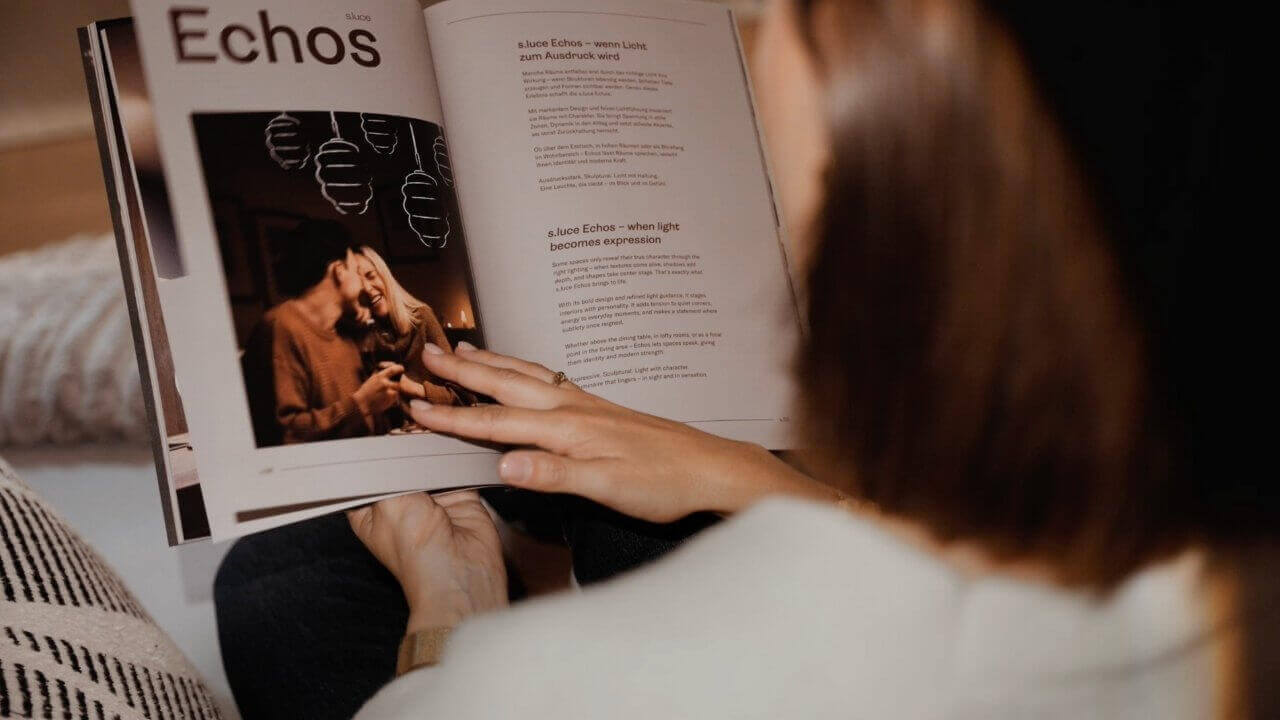 Eine Person blättert durch ein Magazin mit dem Titel "Echos" und betrachtet Fotos und Texte.