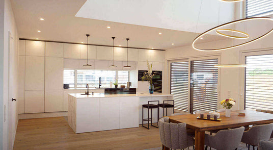 Moderne Küche mit hellem Holzfußboden, eleganter Kochinsel und stilvollen Leuchten.