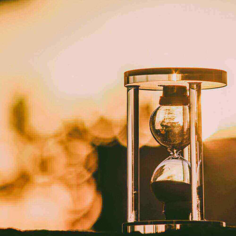 Sonnenuntergang mit einer Sanduhr, die Zeit symbolisiert und eine warme Atmosphäre schafft.