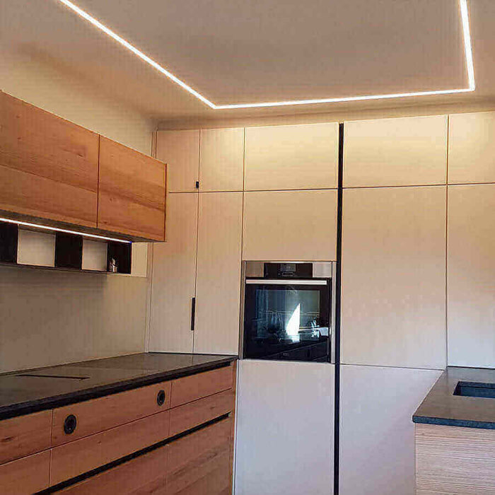 Moderne Küche mit Holzschränken und eleganter Beleuchtung, ideal für stilvolle Wohnräume.