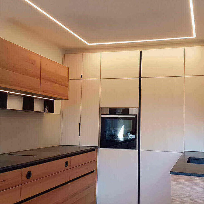 Moderne Küche mit Holzschränken und eleganter Beleuchtung, ideal für stilvolle Wohnräume.