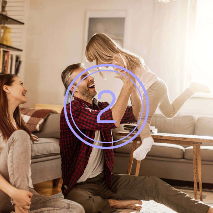 Glückliche Familie spielt im Wohnzimmer, während das Kind vom Vater in die Luft gehoben wird. Gemütliche Atmosphäre.