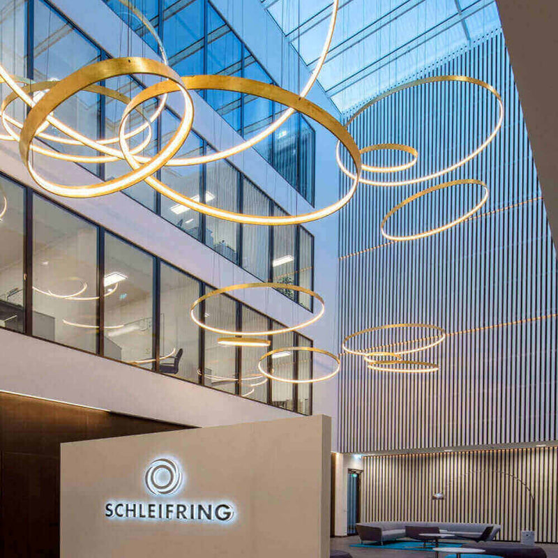 Moderne Büroumgebung mit stilvollen LED-Leuchten und SCHLEIFRING-Logo, hell und einladend.