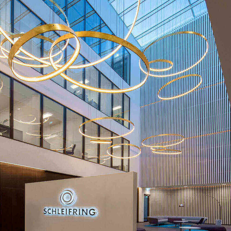 Moderne Büroumgebung mit stilvollen LED-Leuchten und SCHLEIFRING-Logo, hell und einladend.