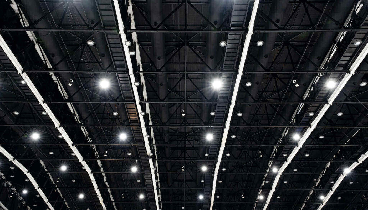 Blick auf das schwarze Dach einer Halle mit hellen LED-Lichtern und sichtbaren Stahlträgern.