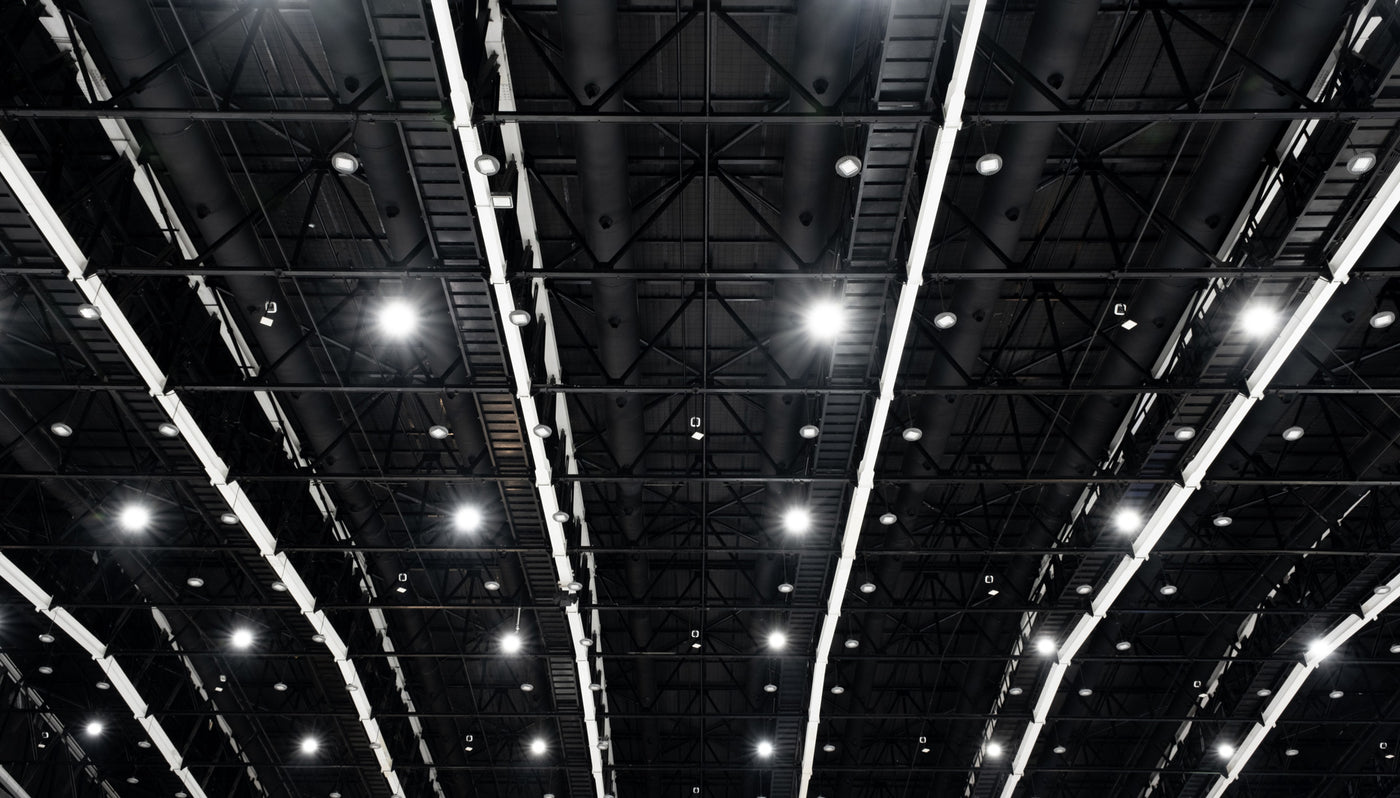 Blick auf das schwarze Dach einer Halle mit hellen LED-Lichtern und sichtbaren Stahlträgern.