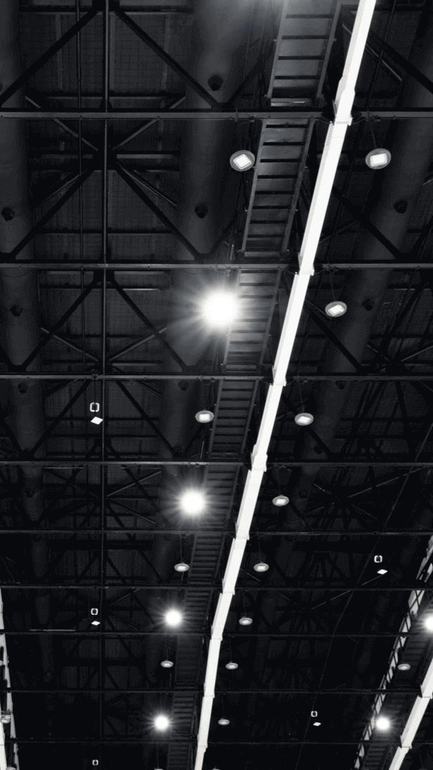 Blick auf die Decke eines modernen Gebäudes mit Lichtern und Stahlträgern im monochromen Stil.