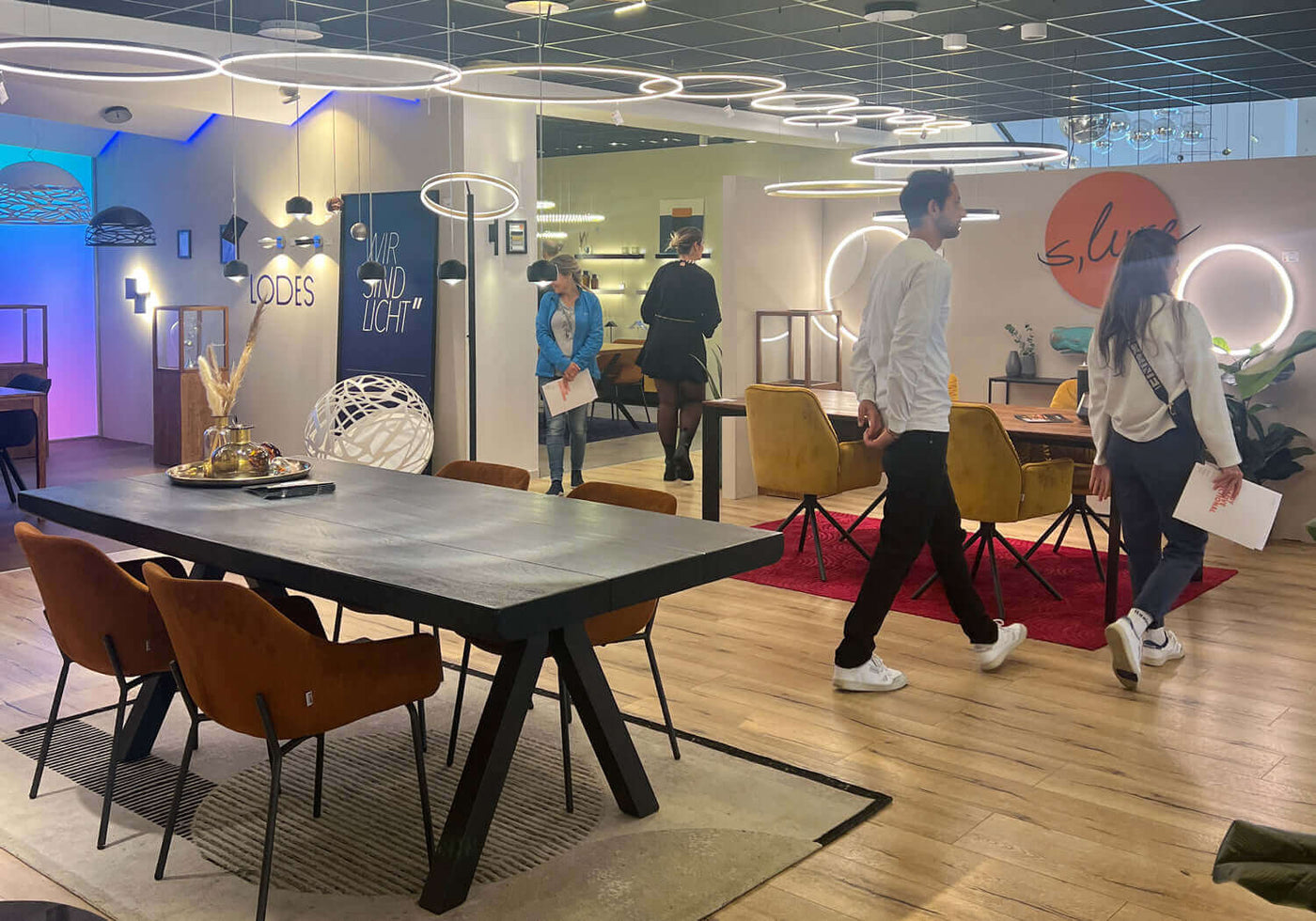 Moderne Einrichtung mit einem Essbereich und Besuchern in einem stilvollen Ausstellungsraum.