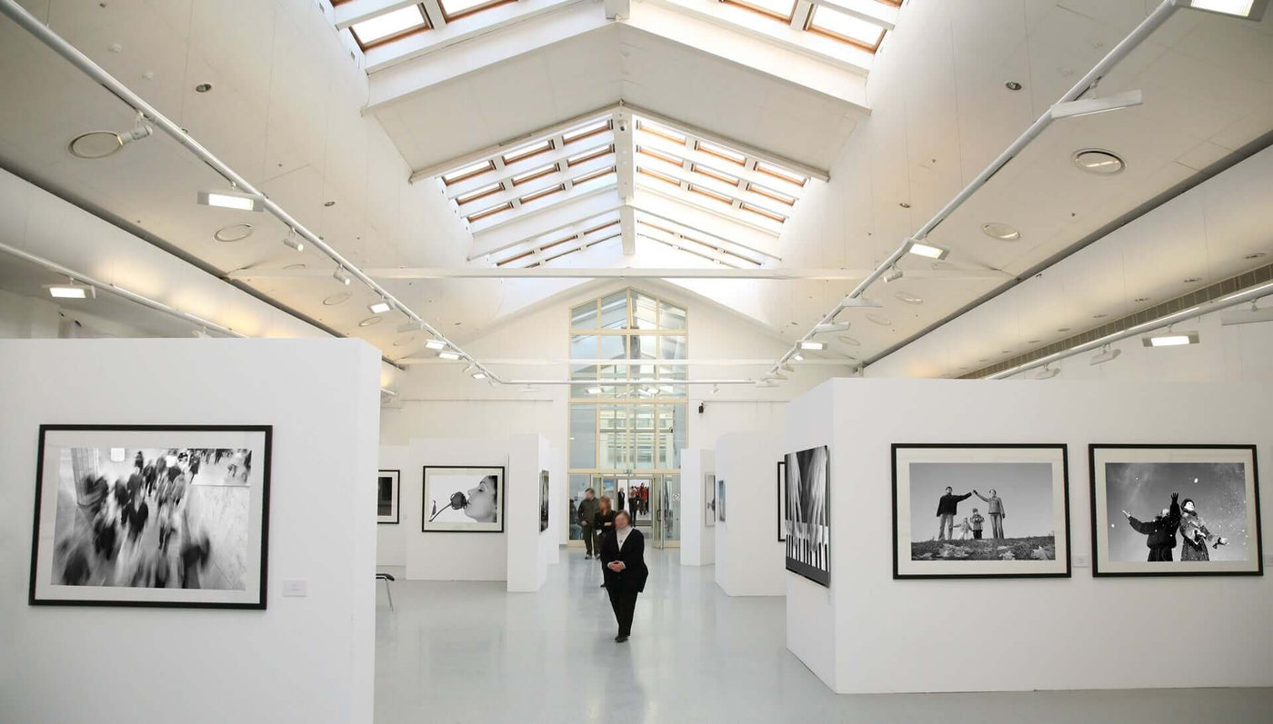 Moderne Kunstausstellung mit schwarz-weißen Fotografien in heller Galerie und Besucher.