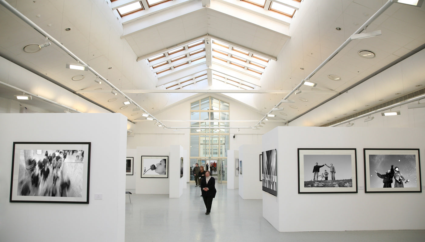 Moderne Kunstausstellung mit schwarz-weißen Fotografien in heller Galerie und Besucher.