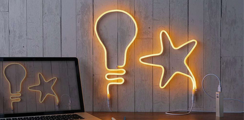Stylische Neonleuchten in Form einer Glühbirne und eines Sterns, die an einer Wand hängen.
