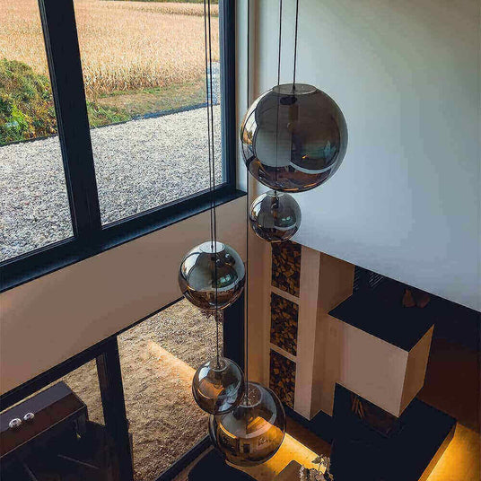 Moderne Hängeleuchten in einem stilvollen Raum mit großen Fenstern und Blick auf das Feld.