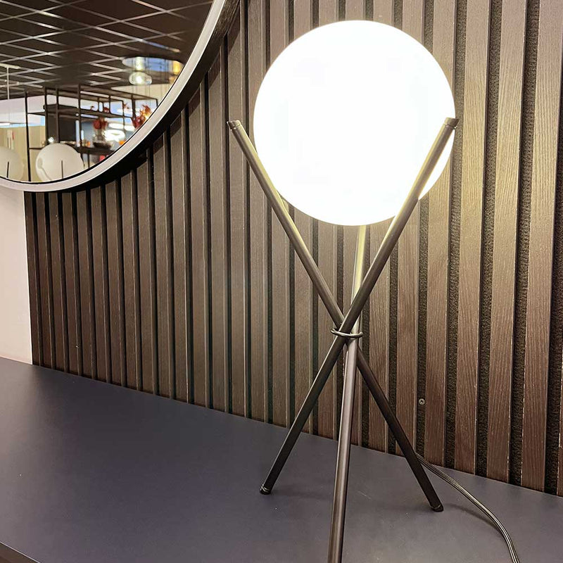 Moderne Tischlampe mit runder LED-Glühbirne auf eleganter Oberfläche mit Spiegel im Hintergrund.