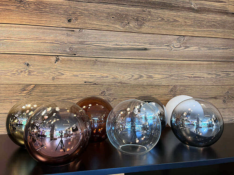 Glas Kugeln in verschiedenen Farben auf einem Tisch vor einer Holzwand, moderne Dekoration.