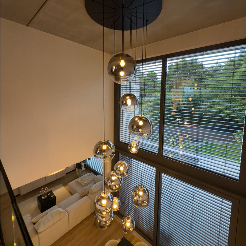 Moderne Pendelleuchten in einem hellen Wohnzimmer mit großen Fenstern und blinden, von oben fotografiert.