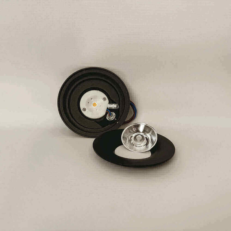 Luce Spiegelreflektor mit schwarzem Sockel und silberner Linse auf grauem Hintergrund.