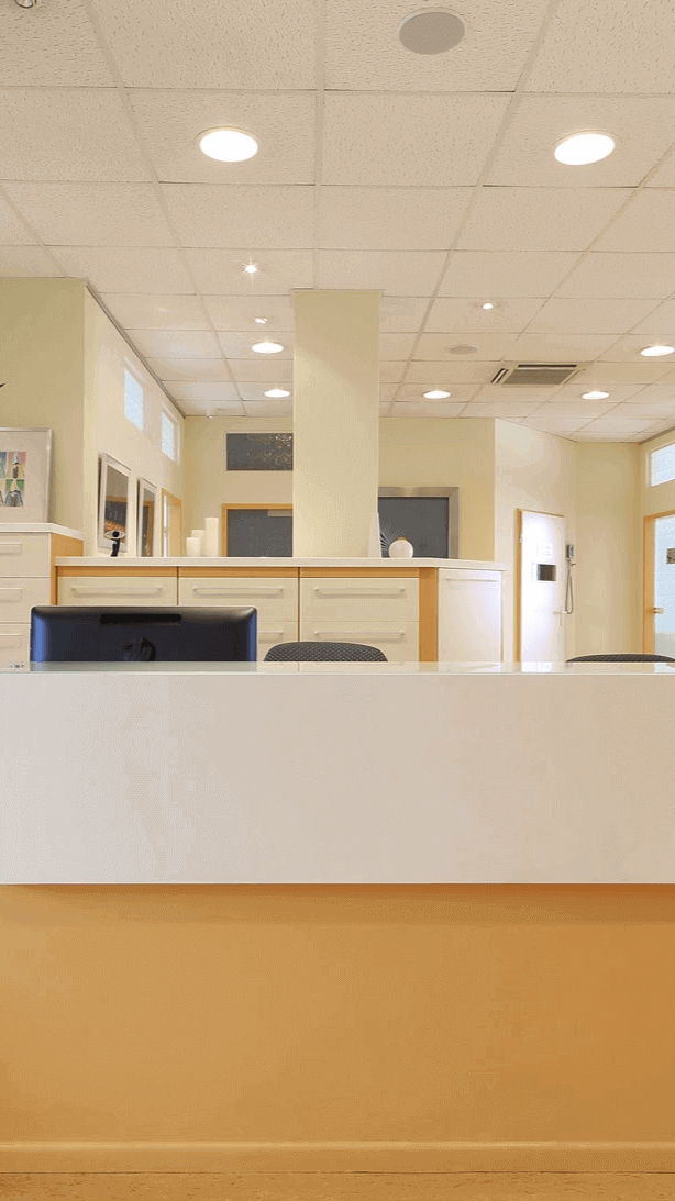 Moderne Empfangstheke in einem hellen Büro mit warmen Farbtönen und eleganten Möbeln.