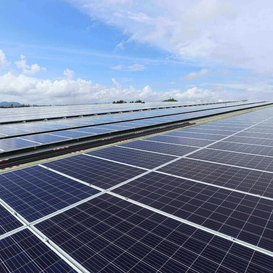 Solaranlage auf einem Dach mit mehreren Photovoltaikmodulen und blauem Himmel im Hintergrund.