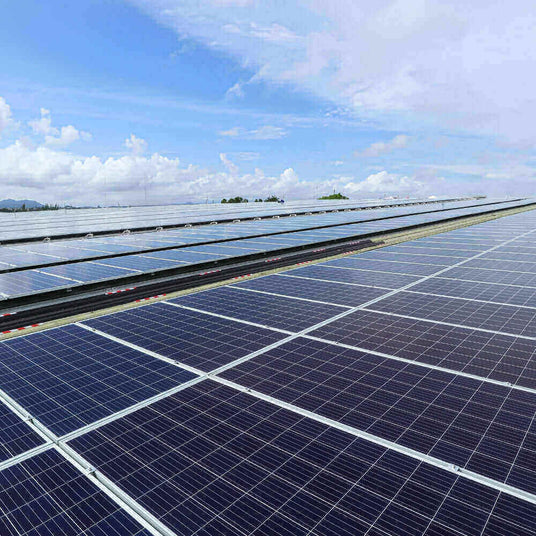 Solaranlage auf einem Dach mit mehreren Photovoltaikmodulen und blauem Himmel im Hintergrund.