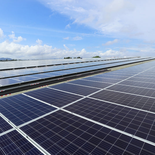 Solaranlage auf einem Dach mit mehreren Photovoltaikmodulen und blauem Himmel im Hintergrund.