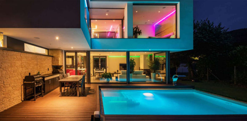Moderne Villa mit Schwimmbad und beleuchtetem Garten bei Nacht, stilvolles Design und entspannende Atmosphäre.
