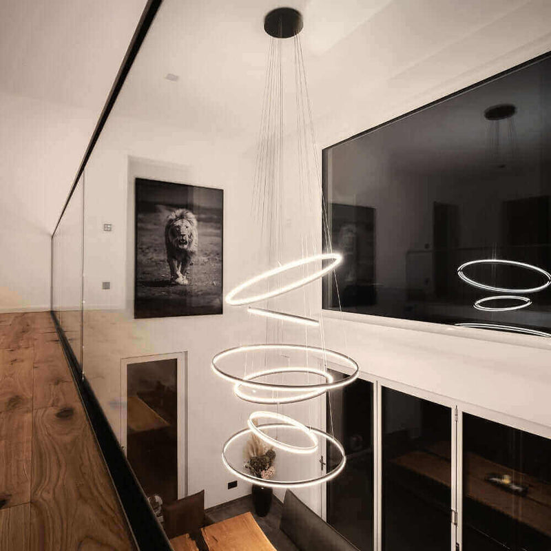 Modernes Lichtdesign mit schwebenden Ringen, beleuchtet einen eleganten Raum mit Kunstwerk eines Löwen.