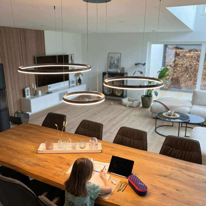 Ein Kind, das am Tisch sitzt und zeichnet, mit modernen Hängeleuchten im modernen Wohnraum.