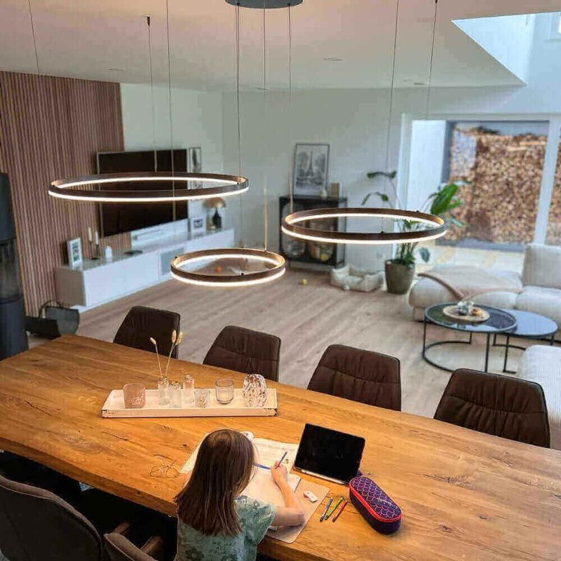 Ein Kind, das am Tisch sitzt und zeichnet, mit modernen Hängeleuchten im modernen Wohnraum.