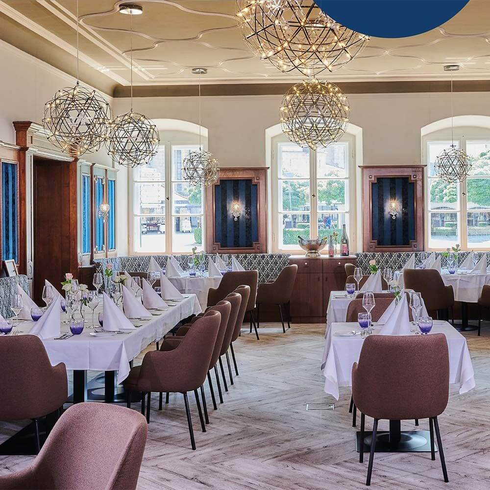 Elegantes Restaurant mit s.luce Atom LED-Hängeleuchten, stilvoll gedeckten Tischen und moderner Einrichtung.