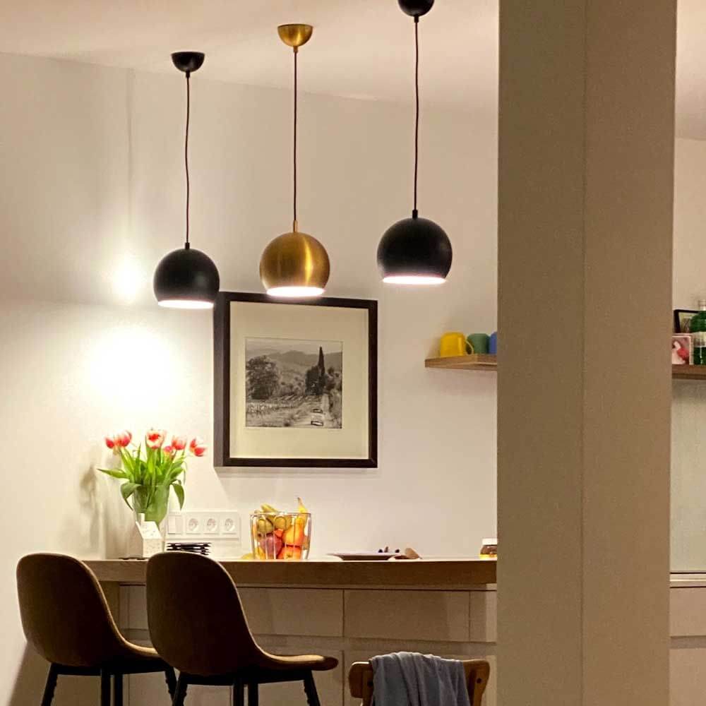 s.luce Ball metall pendellampa med vridbar utbytbar skärm över en modern köksö.