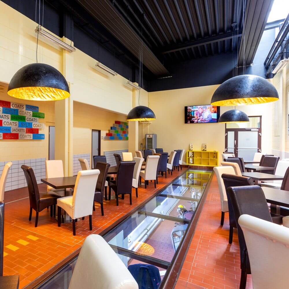 Moderne Restaurantinterior mit s.luce Blister Pendelleuchten, eleganten Tischen und Stühlen.