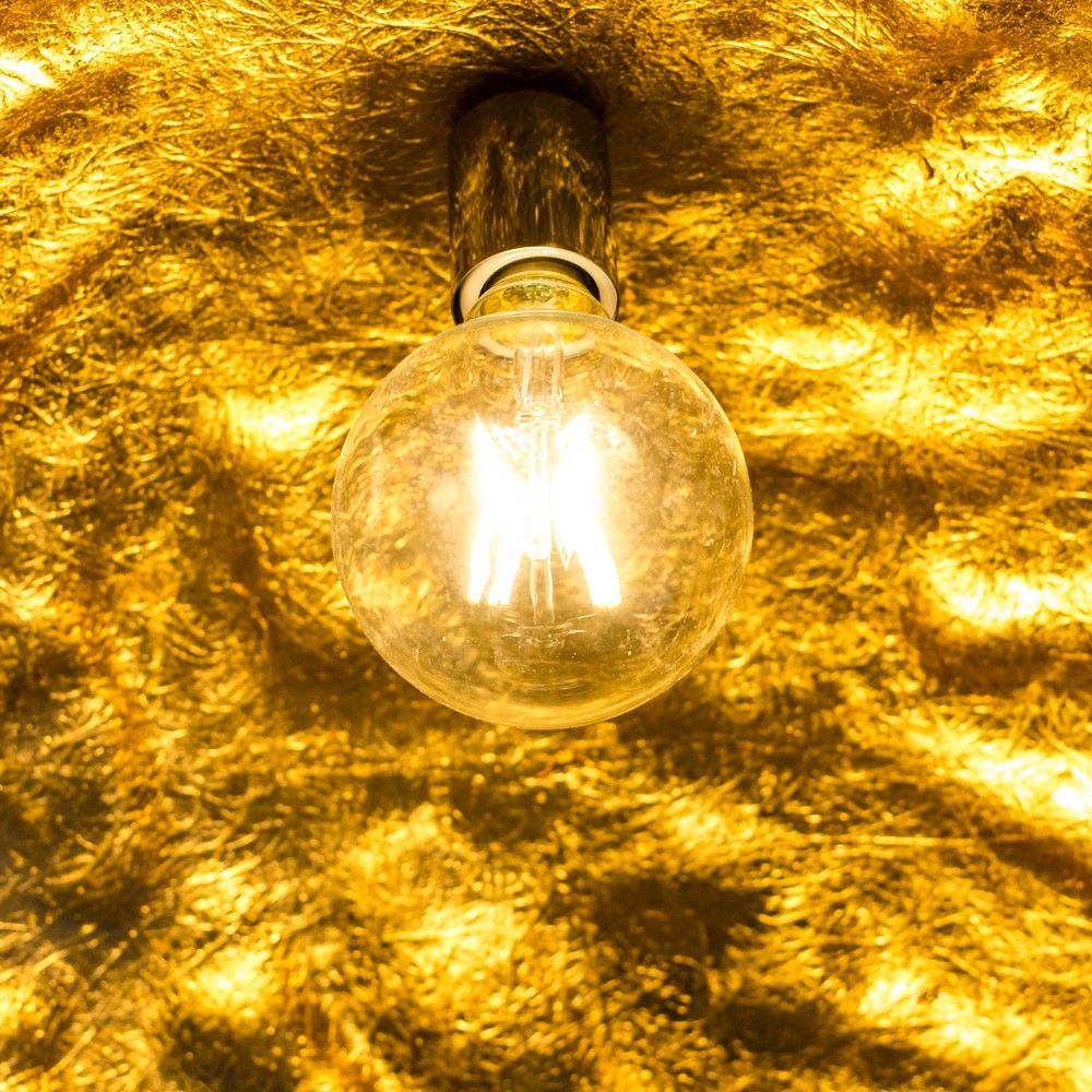 Glühbirne leuchtet vor goldenem Hintergrund, ideal für stilvolle Beleuchtung