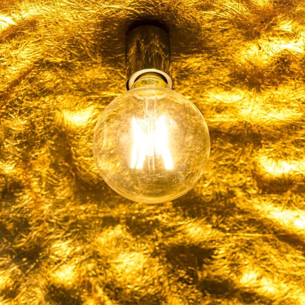 s.luce Blister Pendelleuchte Matt leuchtet strahlend an goldenem Hintergrund.