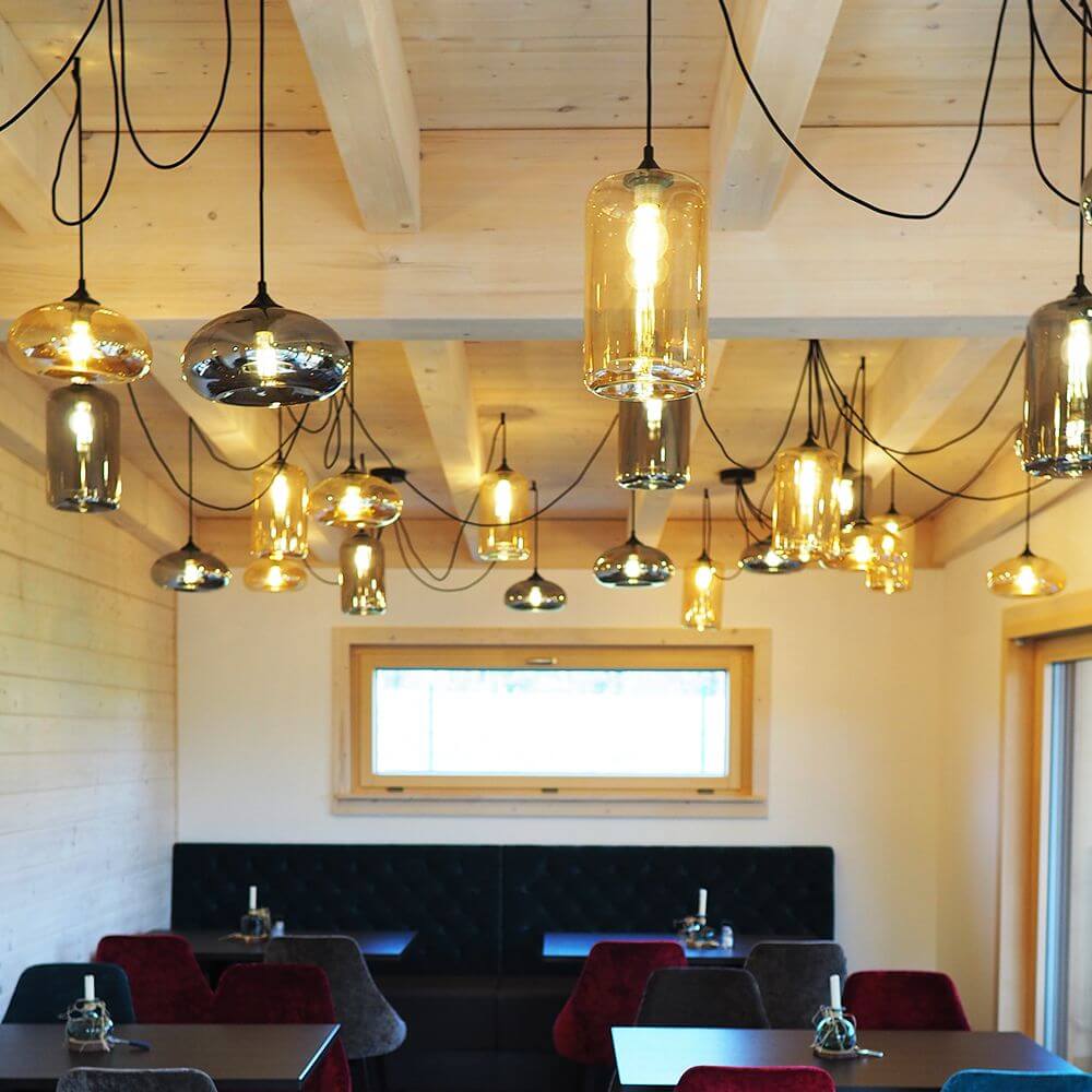 s.luce Cruet Galerie-Pendelleuchte in einem modernen Raum mit Holzdecke und stilvollen Tischen.