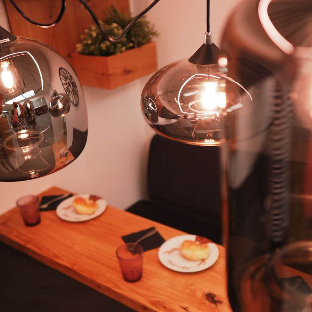 s.luce Cruet Galerie-Pendelleuchte Glas extra lang 5m über einem Tisch mit Speisen und Getränken.