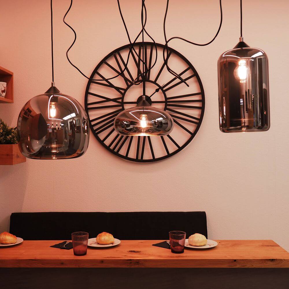 s.luce Cruet Galerie-Pendelleuchte Glas im modernen Raum mit Uhr und Esstisch.